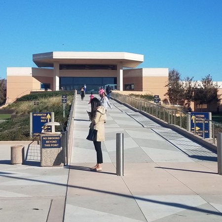 Long entrance ramp leads up to fortress like concrete entrance of Santa Rita Jail against a morning blue sky